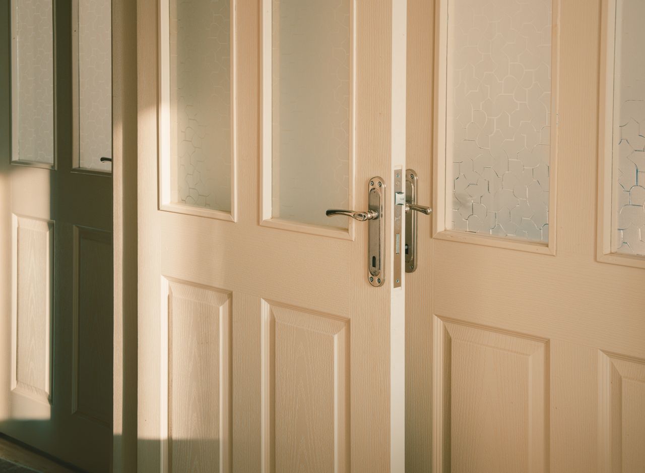 our-experience Elegant wooden doors with frosted glass panels softly illuminated by streaming sunlight.