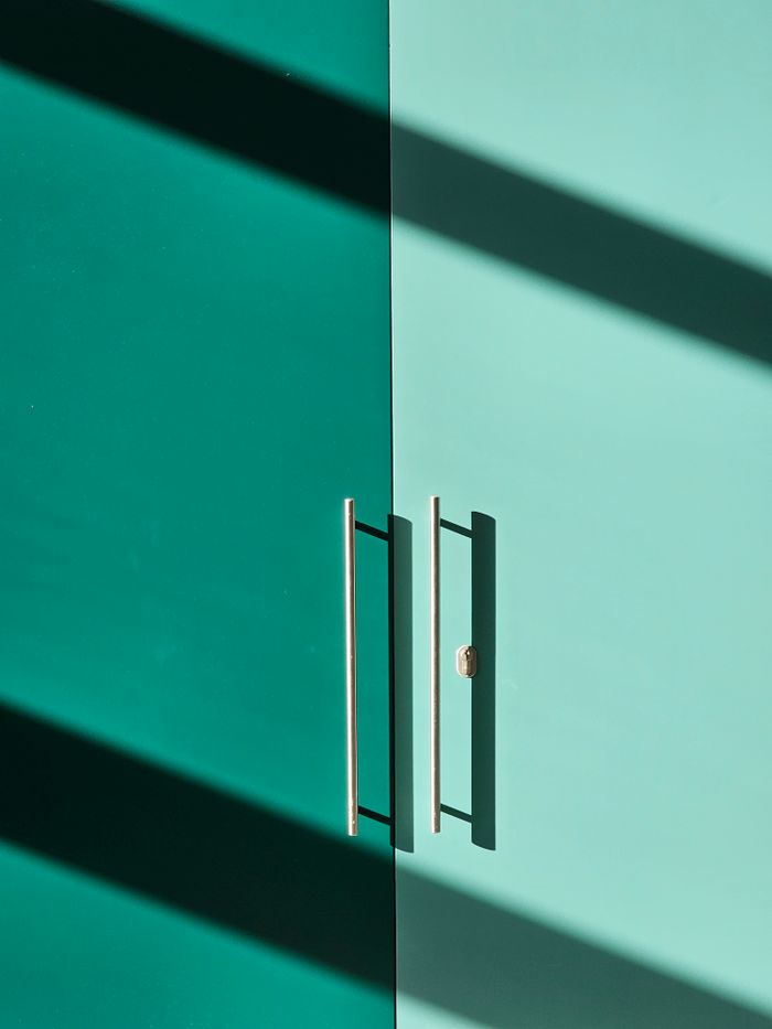 Styled teal doors with linear shadows creating geometric patterns in natural light.