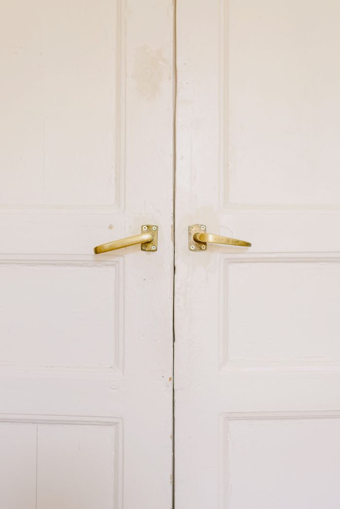 Contemporary wooden building doors with uneven surface and bright metal handles fixed with screws