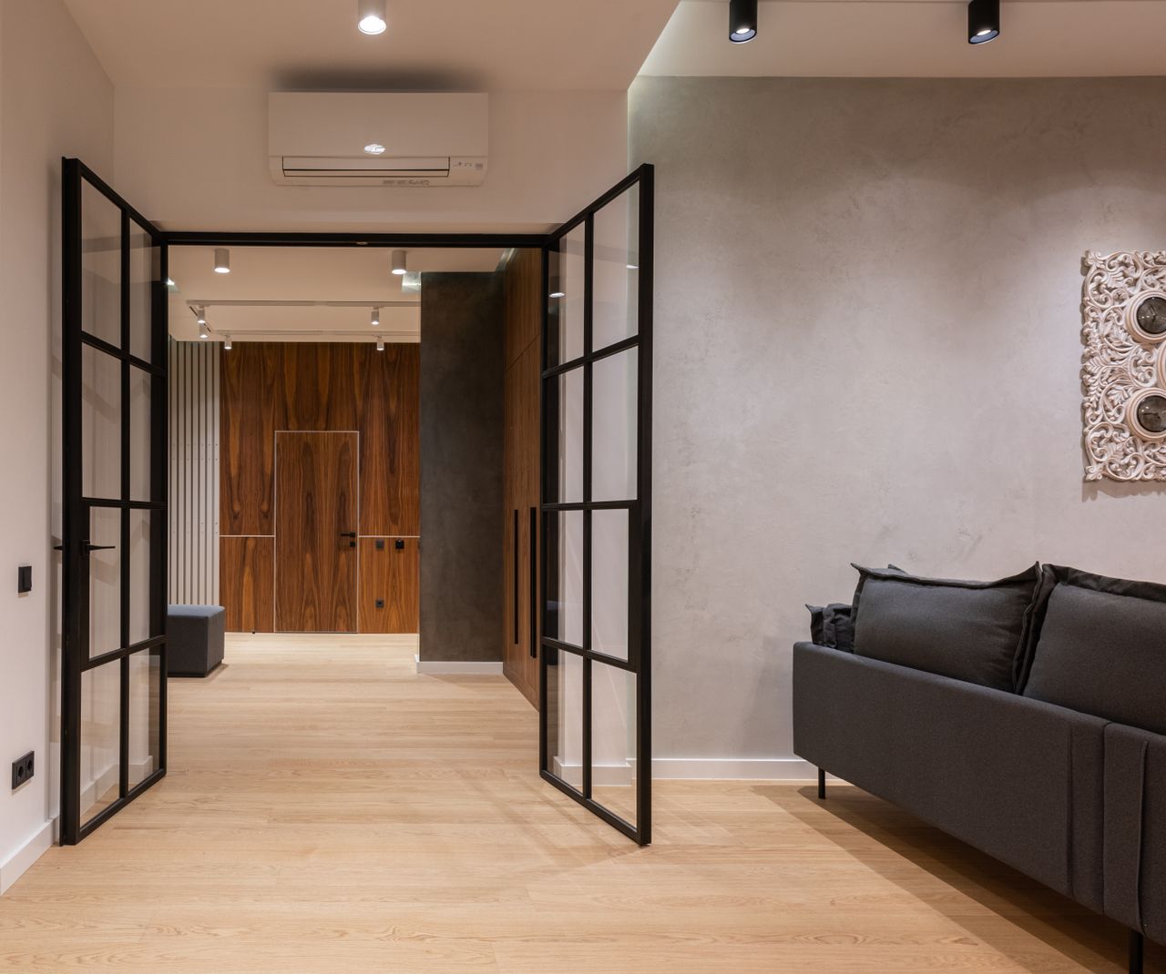 Interior of modern bright house with open doors to hallway near sofa with pillows